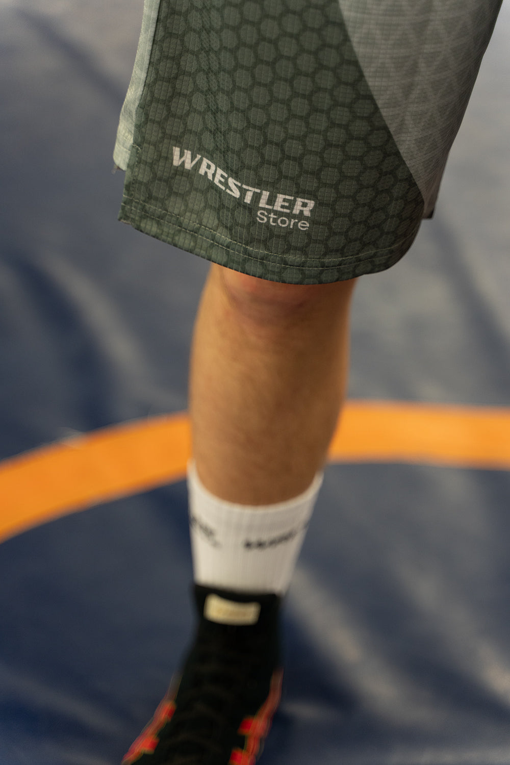 Detailaufnahme der WrestlerStore Trainingsshorts mit Logo und Muster auf der Matte beim Training im WrestlerStore